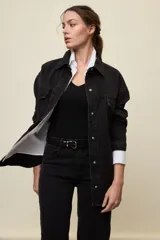 Sobrecamisa de denim de calce amplio y color azul, con cuello clásico, cierre frontal con broches metálicos y bolsillos delanteros con solapa.