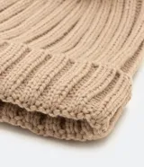 Gorro de punto acanalado en color blanco, con diseño de bajo plegado y pompón superior a tono.