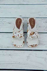 Sandalias con plataforma y capellada de cuero con estampado animal print de vaca en tonos marrón y blanco.