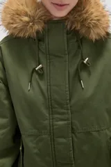 Campera negra de algodón con capucha, cierre frontal oculto y bolsillos laterales. Presenta un diseño holgado con detalles de piel sintética en el borde de la capucha.