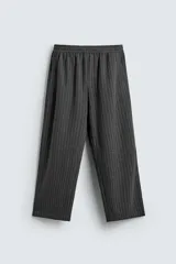 Pantalón de corte baggy fit, color gris oscuro con estampado de rayas verticales finas. Presenta cintura elástica con cordón interior, bolsillos frontales de vivo y bolsillos traseros de plastrón.