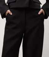 Pantalón de sastrería corte recto, color marrón, con cintura de tiro medio, trabillas largas y bolsillos traseros.