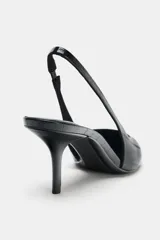 Zapato destalonado de tacón medio fino, con acabado en punta y textura con efecto relieve en el cuerpo. Cuenta con tira trasera elástica ajustable.
