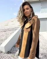 Sobre camisa de gamuza con diseño de paneles verticales en colores marrón, tostado y negro. Presenta cuello clásico, cierre frontal con botones metálicos y un bolsillo en el pecho con solapa.