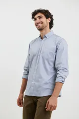 Camisa celeste de algodón con cuello abotonado, manga larga con puños abotonados y bolsillo en el pecho. Corte clásico.