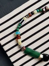 Collar de cuentas multicolor confeccionado con piedras, resina y abalorios de diferentes formas, tamaños y texturas, destacando una pieza rectangular verde central.