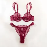 Conjunto de lencería de tul translúcido color bordó con diseño de líneas orgánicas, compuesto por soutiene con aros y breteles con volados, y bombacha colaless ajustable con detalles de argollas doradas.