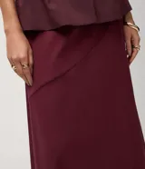 Pollera midi evasê Cortelle de bengalina color bordó, con corte evasé, largo por debajo de la rodilla y detalle de recorte delantero horizontal.