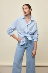 Camisa celeste de corte oversize, con mangas largas, cuello camisero y cierre frontal de botones.