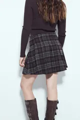 Minifalda tableada con estampado de cuadros en tonos oscuros, de corte acampanado y estilo colegial.