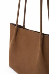 Cartera tipo shopper de gamuza color marrón, con diseño minimalista, formato amplio y asas largas para llevar al hombro.