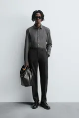 Pantalón de traje regular fit confeccionado en tejido de lana. Presenta bolsillos frontales, bolsillos traseros de vivo con botón y cierre frontal con cremallera y botón.