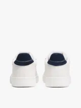 Zapatillas de estilo tenis confeccionadas en piel napa blanca, con diseño de corte bajo y cierre de cordones. Presentan un panel de contraste en el talón en color azul marino, forro de poliéster y suela de goma. Incluyen el parche distintivo de Tommy Jeans en el lateral.