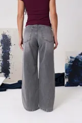 Jean de tiro medio con silueta amplia y corte baggy, confeccionado en denim de algodón con lavado claro desgastado. Cuenta con cierre frontal, botón metálico y bolsillos funcionales.