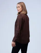 Camisa de manga larga con estampado a rayas verticales marrones y negras. Tiene cuello con solapa, abertura central con botones y bolsillo en el pecho.