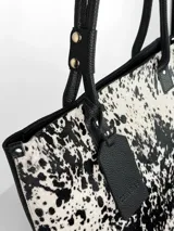 Cartera tipo tote de cuero genuino color marrón oscuro con textura de reptil. Cuenta con doble asa de hombro, cierre superior y un dije colgante de cuero a tono.