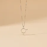 Collar de cadena fina tipo veneciana con dije circular que combina los símbolos de género masculino y femenino, realizado en plata 925.