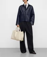 Bolso shopper horizontal negro de piel sintética, con dos compartimentos, cierre magnético y bolsillo interior con cremallera. Cuenta con asa de mano y correa larga regulable y extraíble, además del logo grabado en el frente.