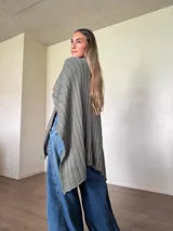 Ruana tejida de algodón con hilo lurex en punto jersey, color azul, con diseño amplio y detalle de etiqueta de cuerina en la parte posterior.