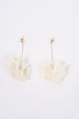 Aros colgantes con diseño de flor de tela en color crema, sujetos por una cadena fina dorada con cierre de perno.