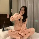 Conjunto de pijama de dos piezas confeccionado en tela plush suave y abrigada. Incluye una remera de manga larga con cuello redondo y un pantalón largo de corte holgado. Presenta un estampado integral de frutas y flores sobre un fondo rosado.