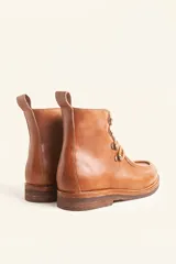 Bota de cuero vacuno color bordó con acabado charol, diseño de caña media con cordones y ganchos metálicos. Presenta costuras visibles en la puntera y suela de goma tipo crepe.