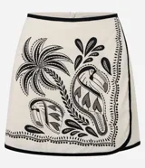 Short pollera de viscolino color crudo con estampa tropical en negro que presenta palmeras y tucanes. Cuenta con cintura fija, cierre posterior con zíper y detalle de vivo contrastante en los bordes.