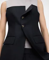 Top combinado de efecto doble prenda con base gris de rayas y capa superpuesta azul marino tipo chaleco sastrero, con cuello redondo, manga sisa, botones frontales y bolsillos con solapa.