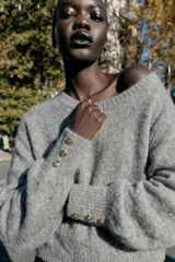 Jersey de punto Zara, color gris, con cuello redondo, manga larga abullonada y puños ajustados con detalle de botones metálicos.
