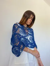 Poncho azul tejido a mano con diseño calado y detalle de mostacillas en el borde.