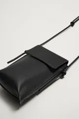 Bandolera de piel color negro con acabado grabado, compartimento principal con solapa imantada y asa fina ajustable.
