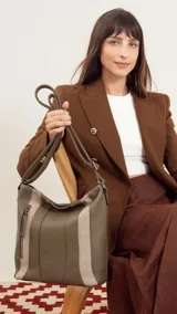 Cartera bandolera color marrón con detalles en gamuza. Tiene correa regulable, cierre metálico frontal y trasero, y división interna.