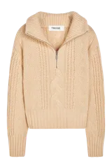 Sweater tejido color crema con cuello alto y cierre metálico frontal parcial.