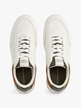 Zapatillas de corte bajo estilo retro baloncesto, confeccionadas en piel blanca con paneles de textura a contraste en color marrón y verde oliva en el talón. Presentan suela de goma dentada, cierre con cordones y logo de Tommy Hilfiger en el lateral y la lengüeta.