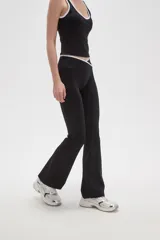 Calza flare de poliamida color negro, con diseño de tiro bajo y detalle de costura cruzada en la cintura.