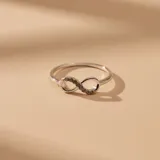 Anillo de plata 925 con diseño de símbolo de infinito, decorado con pequeñas circonias incrustadas en una de sus curvas.