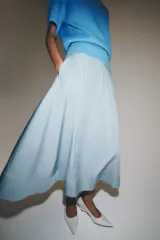 Falda midi de tiro alto en color negro, con diseño en línea evasé y cierre de cremallera oculta en la costura.