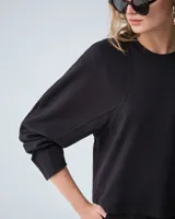 Buzo negro de punto tramado italiano con mangas voluminosas, escote redondo y detalles de bordado en sisas y recortes de manga.