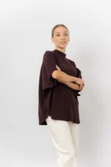 Sweater de tejido de punto color negro, con cuello semi alto y mangas cortas amplias. Presenta una silueta relajada y caída fluida.