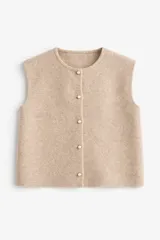 Chaleco de punto color beige, con cuello redondo y cierre frontal de botones con detalle de perlas.