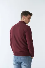 Sweater verde con medio cierre, tejido en buttoné, de manga larga y calce regular.