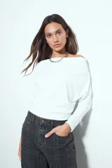 Top de manga larga con escote bote amplio, diseñado para usar ligeramente caído sobre los hombros. Presenta una silueta entallada y tejido liso, liviano y adaptable al cuerpo.