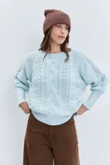 Sweater de punto en color celeste, con diseño de trenzas y textura en relieve. Presenta cuello redondo, mangas largas con puños ajustados y un corte holgado.