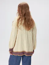 Cardigan oversize de punto color fucsia, con diseño trenzado, cuello en V y detalles en marrón y violeta en la botonera, bolsillos delanteros, puños y ruedo.