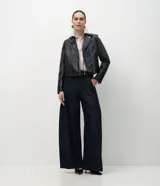 Campera estilo biker de poliuretano, con cierre frontal asimétrico, cuello con solapas y cremalleras en los puños. Presenta un diseño entallado con acabado liso.