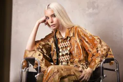 Camisa de corte oversize con mangas 3/4, confeccionada en una combinación de terciopelo y encaje con diseño floral. Presenta cuello clásico y una textura rica y elaborada.