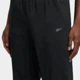 Pantalón deportivo Reebok negro, de tejido ligero y corte ajustado (slim fit), con cintura elástica, bolsillos laterales y bajos elásticos. Presenta el logo Vector estampado en el lateral de una de las perneras.