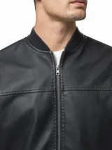 Campera tipo bomber de cuero sintético color negro, con cierre frontal completo, bolsillos laterales con cierre y puños, cuello y ruedo de tejido acanalado.