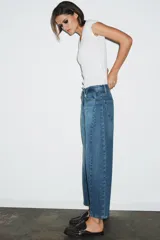 Jeans de tiro medio con corte relajado y largo al tobillo. Presenta diseño de cinco bolsillos, trabillas en la cintura y cierre frontal con cremallera y botón metálico.