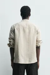 Camisa de corte regular confeccionada en tejido con mezcla de modal, con diseño de rayas verticales, cuello solapa, manga larga con puños abotonados y cierre frontal de botones.